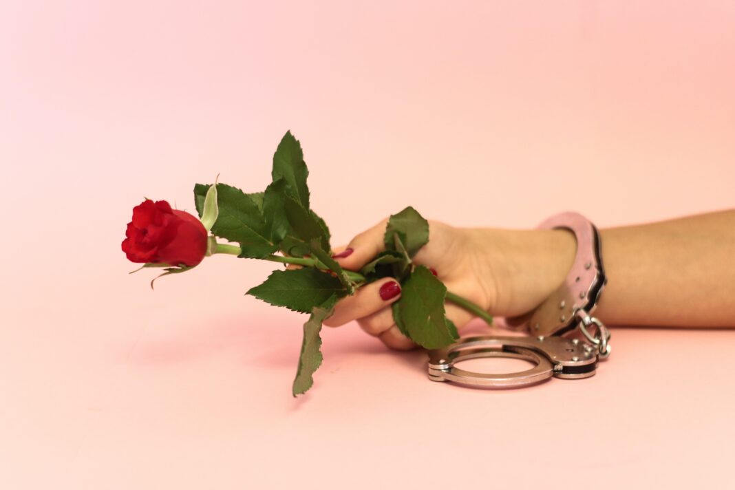 cuffing season, handcuff holding rose